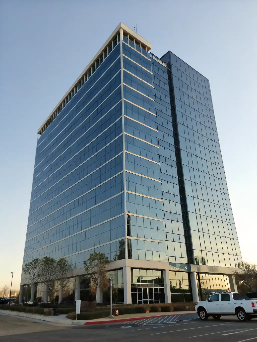 A commercial building with professionally tinted windows, reflecting the surrounding landscape and showcasing the sleek, energy-efficient appearance achieved by Mahalo Worx.